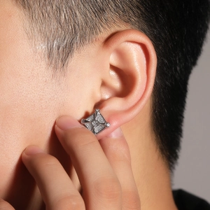 Close-up of a silver cross earrings with square zircon crystals worn by a model