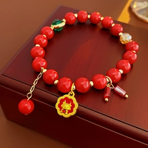 Détail du bracelet en perles d'agate rouge avec pendentif floral doré sur boîte à bijoux