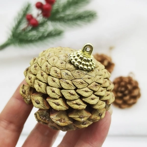 Close-up of a natural brown pinecone ornament with a golden metal loop for hanging
