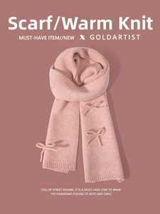 Detail of pink knitted scarf featuring a 3D bow accent and textured ribbed edges