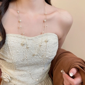 Detail of elegant double-layered pearl necklace on a model with golden chain and white pearls