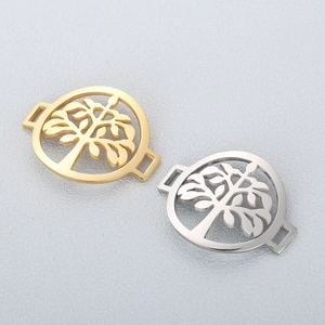 Macro shot of gold and silver hollowed tree of life charms on grey texture background