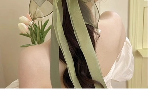 Detail of avocado green chiffon hair bow with pearls on low ponytail hairstyle