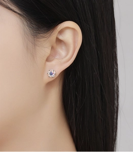Close-up of a model wearing a classic round-cut stud earring in silver finish