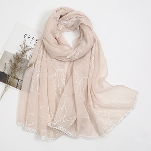 Pale pink cotton linen scarf with white floral embroidery and lace edges on white surface