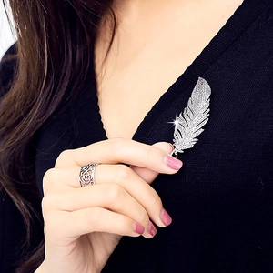 Elegant silver feather brooch with zircon crystals pinned on a black knit sweater