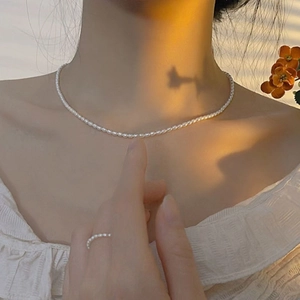 Close-up of elegant ultra-fine freshwater pearl necklace and matching ring on model
