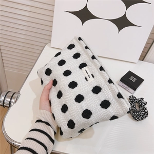 Détail d'une trousse à maquillage en tricot à pois noirs avec étiquette simple wish