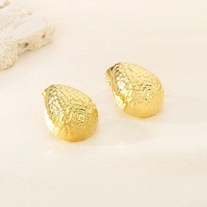 Macro shot of gold teardrop earrings featuring a hammered texture and minimalist design