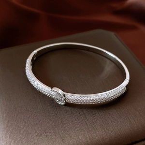 Macro detail of silver horseshoe bangle with pave crystals on a jewelry box