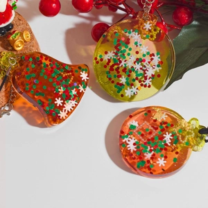 Détail de pendentifs de Noël en résine avec paillettes festives et chaînes métalliques