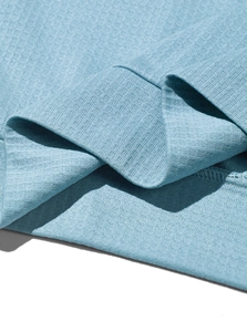 Detail view of light blue knitted fabric texture and ribbed hem on the men's polo shirt