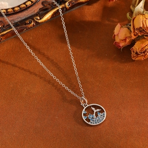 Detailed view of silver whale tail pendant necklace with blue zircon on velvet
