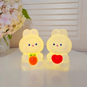 Detail of warm glowing rabbit night lights holding carrot and heart for cozy home decor