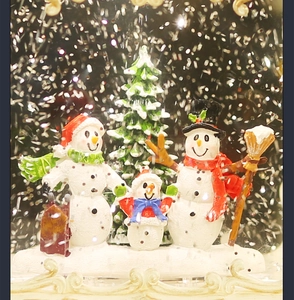 Macro detail of Christmas snow globe featuring a snowman family and a festive tree