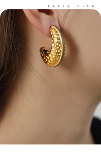 Close-up of golden C-shaped hoop earrings with unique honeycomb texture on model