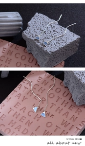 Detail of blue Mount Fuji ear threads on textured stone and pink embossed board