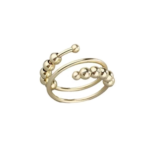 Macro detail of golden anxiety ring with rotating metal beads and adjustable open band