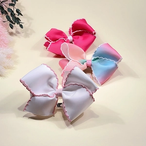 Détail des barrettes nœuds arc-en-ciel avec bordures festonnées pour petites filles