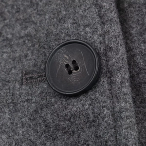 Macro shot of dark gray wool fabric texture and black button on a women's coat