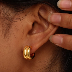 Detailed close-up of double-layer gold C-shaped hoop earring on ear with polished finish