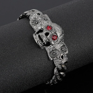 Detail of gothic punk skull bracelet with red crystal eyes on a black pedestal