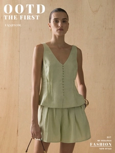 Detail of pale green V-neck vest featuring fabric buttons and matching high-waist shorts