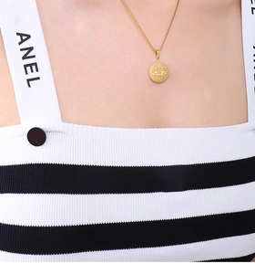 Close-up of gold titanium steel necklace with a round scales pendant on a model's neck