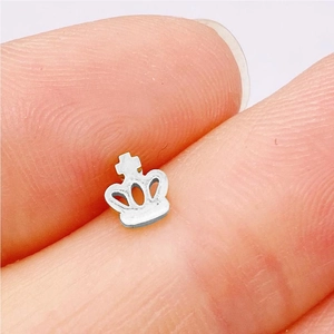Close-up of a silver crown stud earring held between fingers showing tiny intricate details