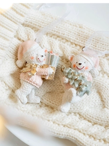 Close-up of resin Christmas polar bear ornaments with pink hats and gift on knit sweater