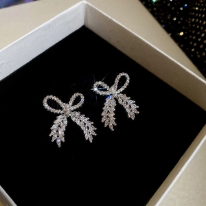 Detailed view of silver bow earrings with sparkling cubic zirconia on black velvet