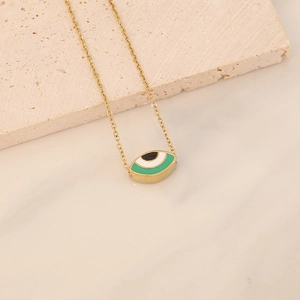Detail of a gold eye pendant with green and white enamel on a matching gold chain