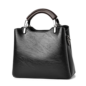 Minimalist black textured leather handbag with brown top handle and silver hardware