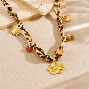 Detail of bohemian necklace featuring leopard print silk scarf with golden sun and flower charms