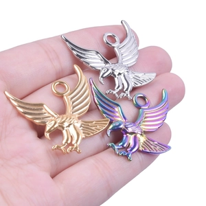 Close-up of eagle animal charms in gold, silver and rainbow colors held in a hand