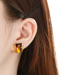 Close-up of vintage square amber gemstone earrings with golden frame on model