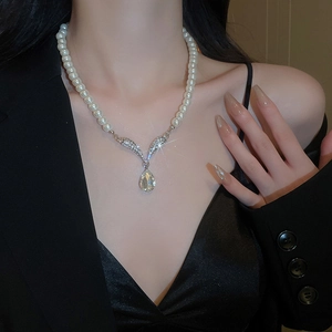 Close-up of pearl necklace featuring a diamond water-drop pendant and V-shaped connector