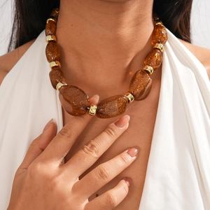 Macro detail of amber resin beads with gold flakes and metallic rings on the necklace