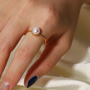Elegant adjustable gold ring with a single freshwater pearl on silk background