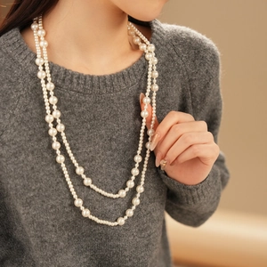 Close-up of double-layer long pearl necklace on model for autumn winter styling