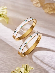 Detail of 18k gold plated stainless steel bangles with white enamel and blue evil eye charms
