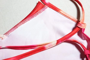 Close-up of red pink gradient dress fabric with precise double-needle stitching detail