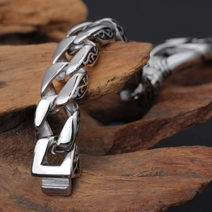Macro shot of silver vintage totem engravings on a thick stainless steel chain bracelet