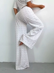 Detail of high-waisted wide-leg pajama pants with red floral print on white fabric
