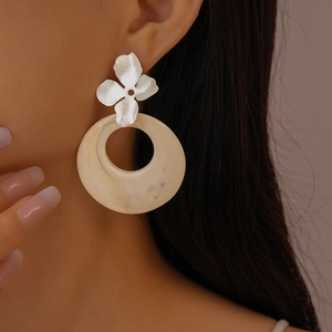 Close-up of model wearing silver flower earrings with beige marble resin rings