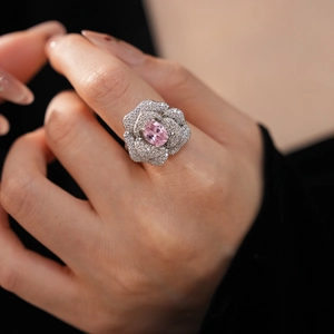 Detail of rose-shaped silver ring with pink oval gemstone and pave zircon on hand