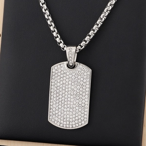 Macro view of iced-out silver dog tag pendant with sparkling rhinestones on box chain