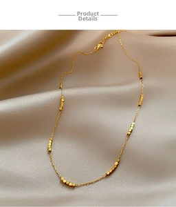 Detail of a vintage gold beaded necklace with geometric cubes on champagne satin silk