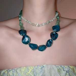 Close-up of double-layered acrylic necklace with irregular green and blue marbled beads