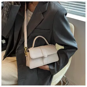 Détail du sac à bandoulière blanc avec fermoir doré et surpiqûres sur un mannequin moderne